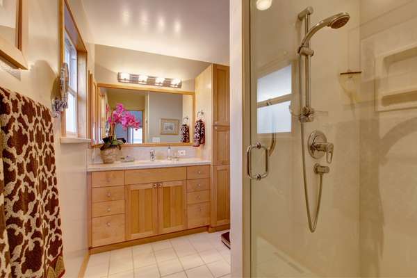 A built-in mirror in rich dark wood holding shelves in bathroom